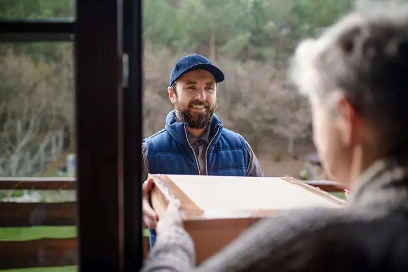 Man courier delivering parcel box to senior woman