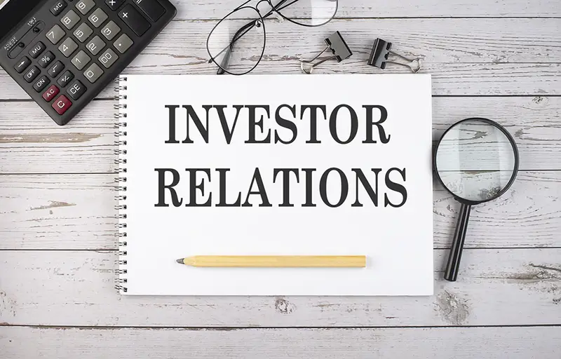 Blank notebook with text INVESTOR RELATIONS on the white background with calculator