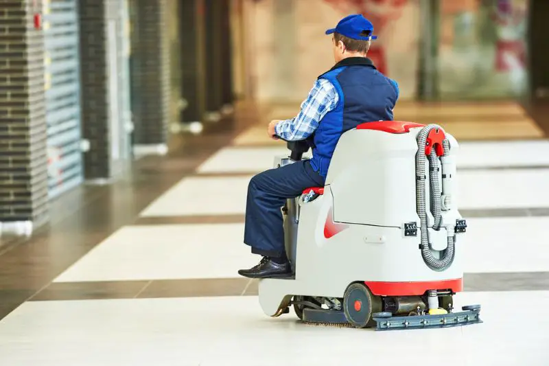 Worker cleaning store floor with machine