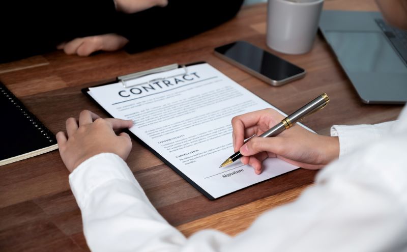 Closeup hand signing contract document with pen