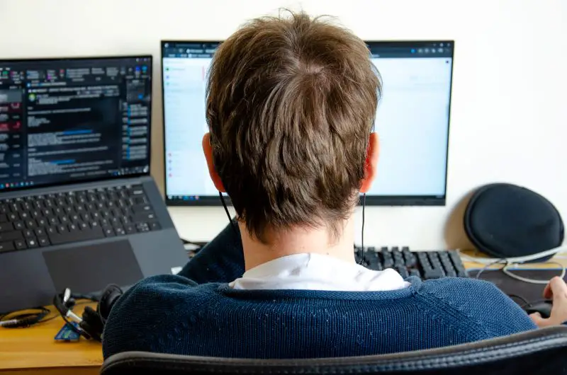 a man working on computer monitor seen from back