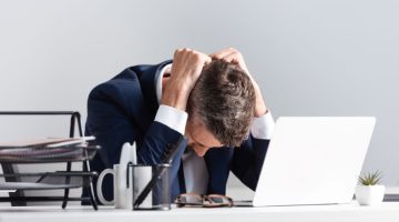 Tired businessman sitting near laptop and documents