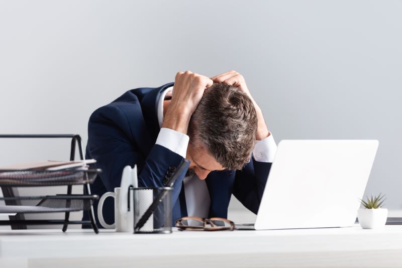 Tired businessman sitting near laptop and documents