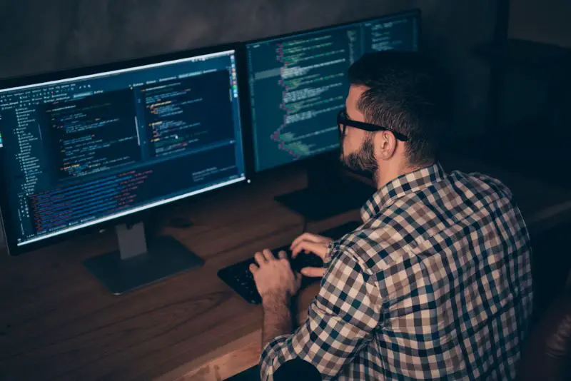 Software developer working on two computer monitor