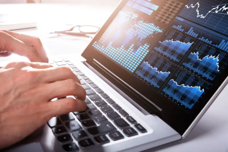 Close-up Of A Businessman's Hand Analyzing Graph on laptop