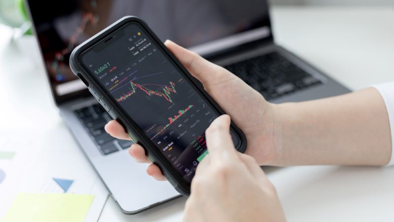 Hand of a young business woman holds a phone with a trading graph