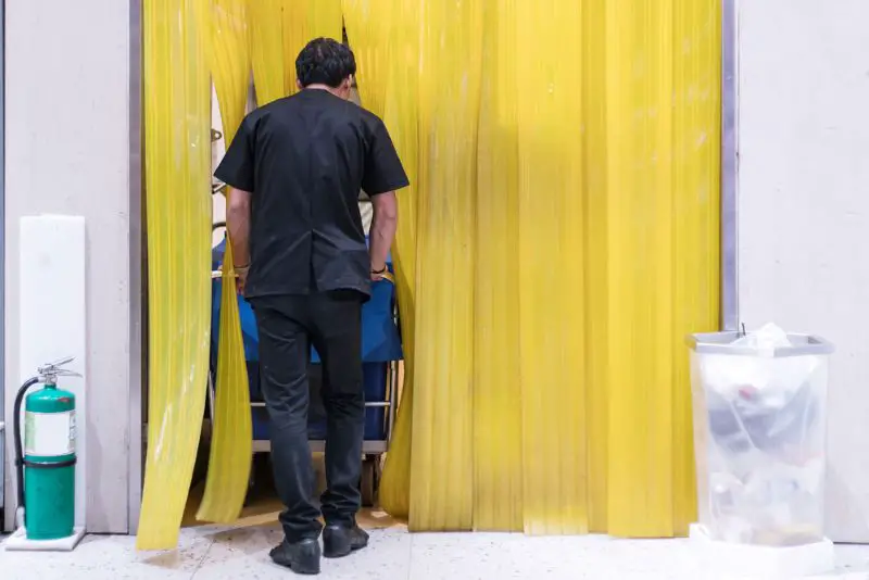 Staff pushing a cart through a plastic air curtain