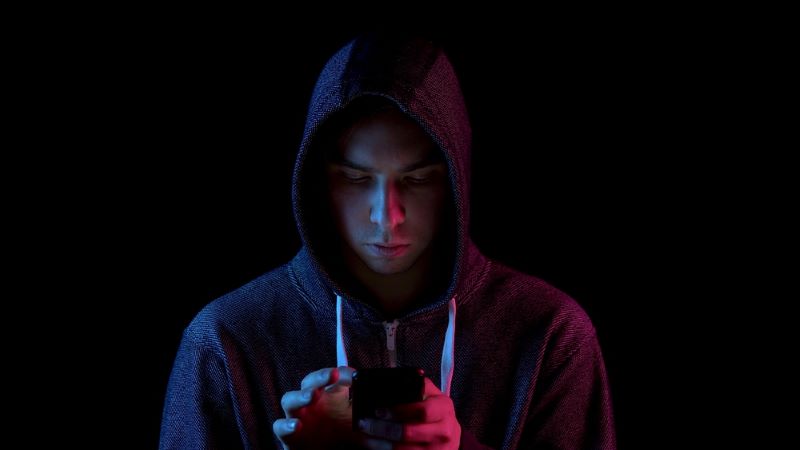 A young man in a hood with a phone in his hands