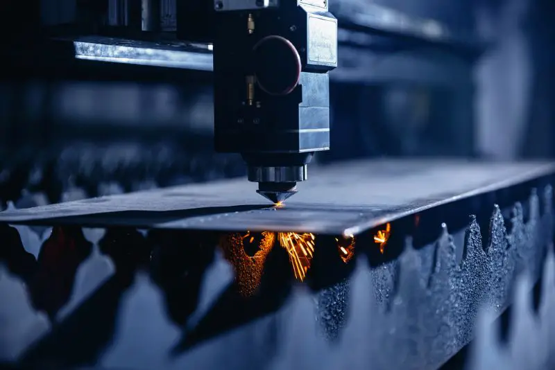 CNC laser machine cutting sheet metal with light spark