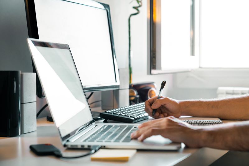 Person working from home at their desk with computers —