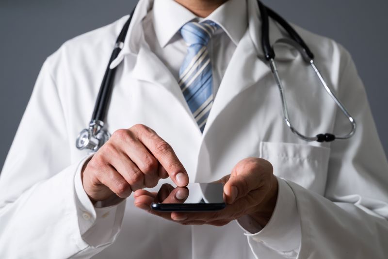Close-up Of A Doctor's Hand Using Smartphone In Clinic