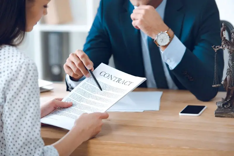 Cropped shot of a woman holding papers and lawyer pointing with pen at details in a contract