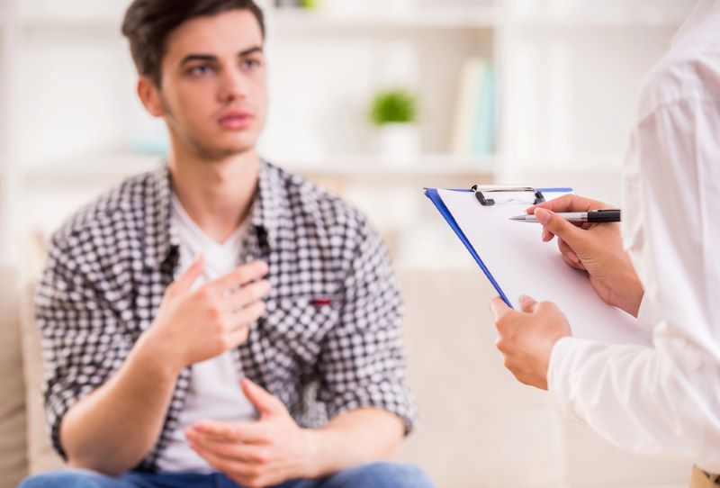 Young man talking to counselor who is writing notes