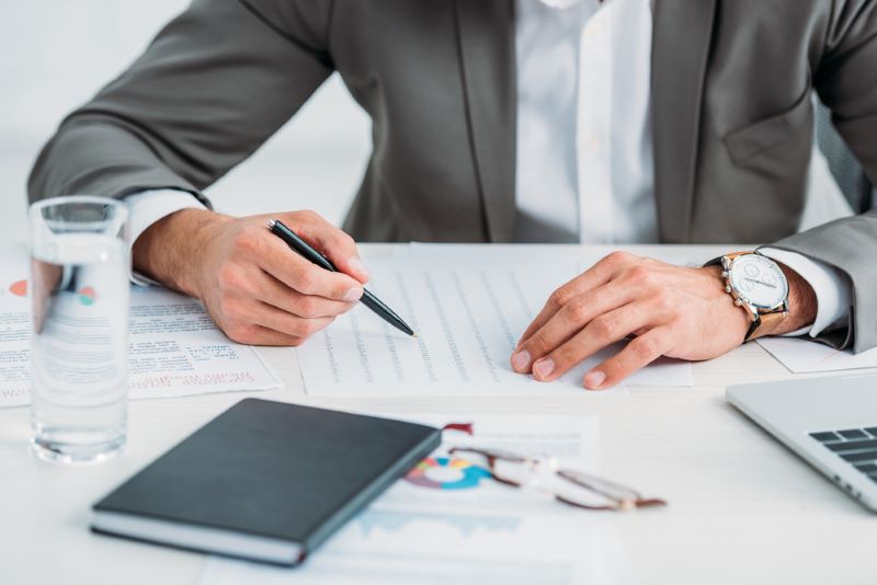 Cropped view of man in formal wear holding pen and doing paper work