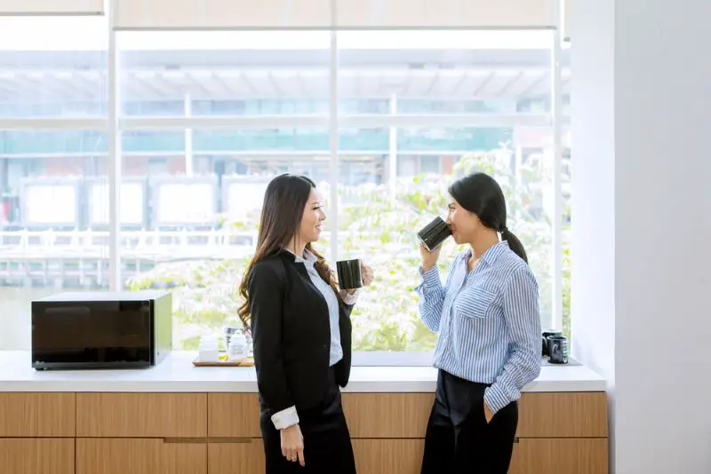 businesswomen sipping a cup of coffee in office pantry