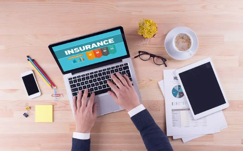 A businessman working at a desk on a laptop showing insurance information