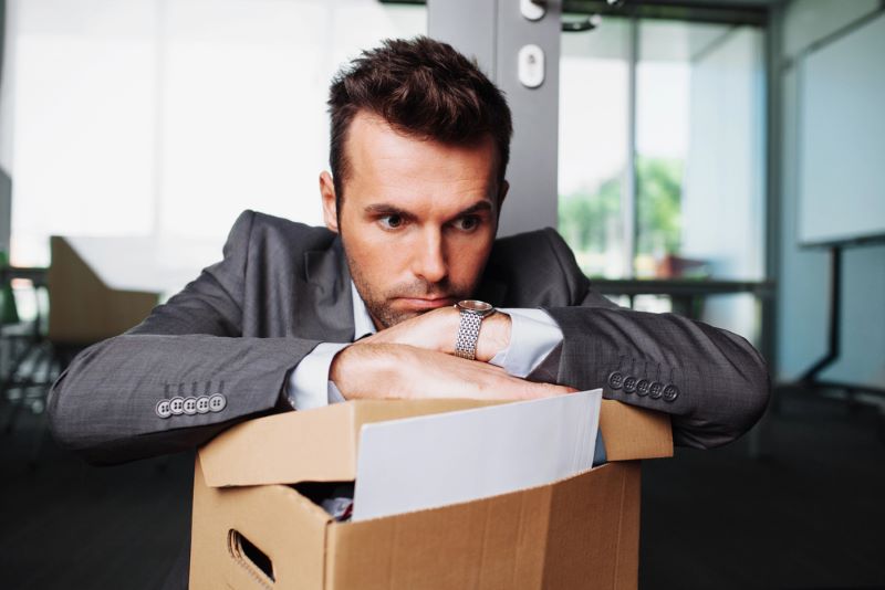 Employee sitting down with a box of personal possessions from work