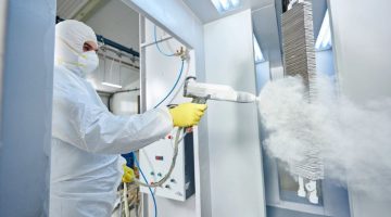 Industrial metal coating. Man in protective suit, wearing a face mask