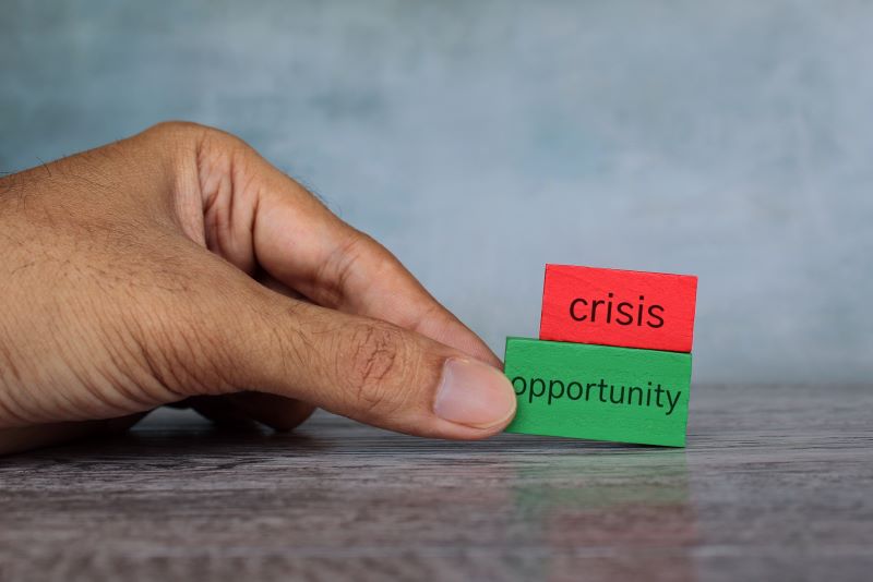 Hand pick wooden cube with text OPPORTUNITY over CRISIS.