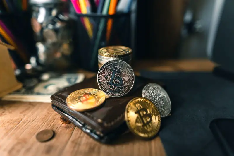 Bitcoin coins on a wallet on a wooden desk