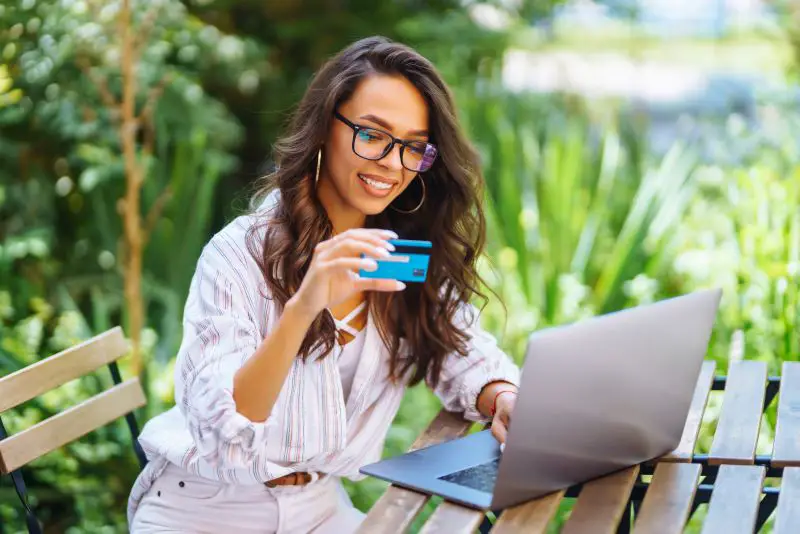 Young woman sitting at cafe making online shopping, using credit card and laptop. Online shopping.