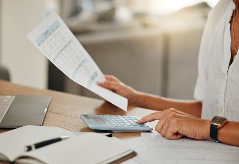 Hands, small business finance and calculator for budget, expenses, invoices or paper bills at home.