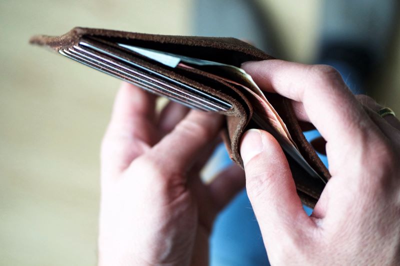 Hands holding the wallet. He wants to pay with some cash.
