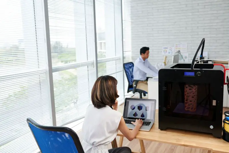 Female designer creating various figures on 3D printer