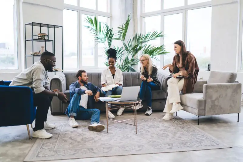Group of multiethnic coworkers discussing work together in modern room