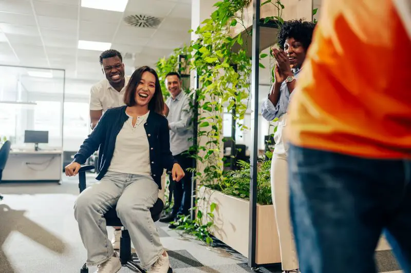 Asian woman and african american man participate in an office chair race