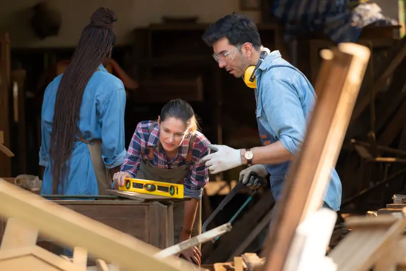 Carpenter and his assistant working together in a carpentry workshop