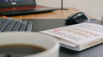 Atomic Habits by James Clear on desk next to keyboard mouse and laptop