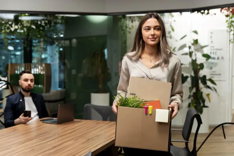 Female in office carry a box of her possessions