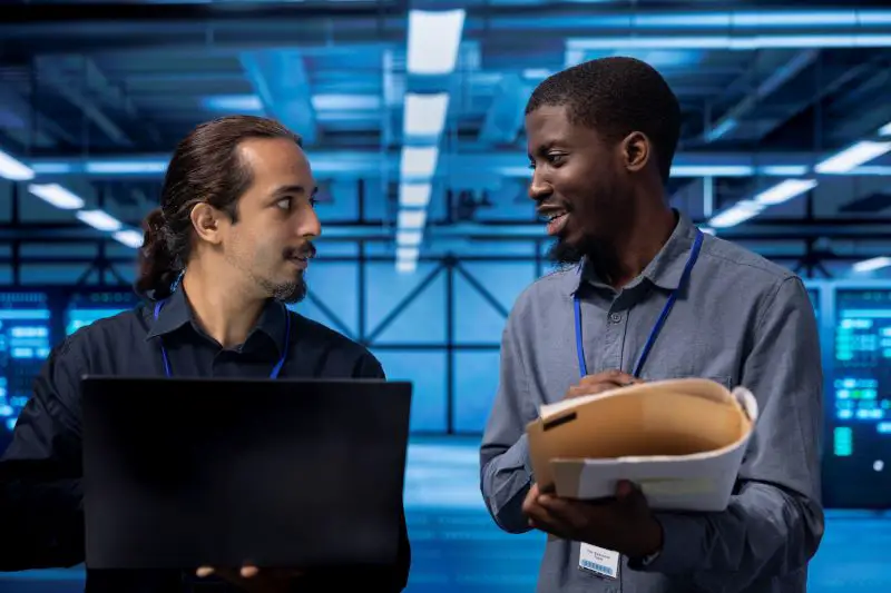 Smiling engineer inspecting server room equipment, checking files