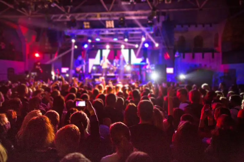The silhouettes of concert crowd in front of bright stage lights