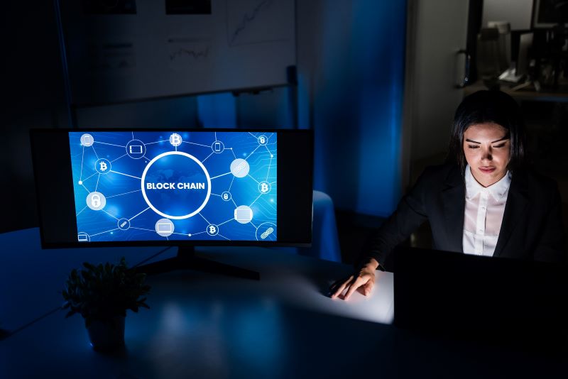 Young business woman working at night inside fintech company office doing blockchain research