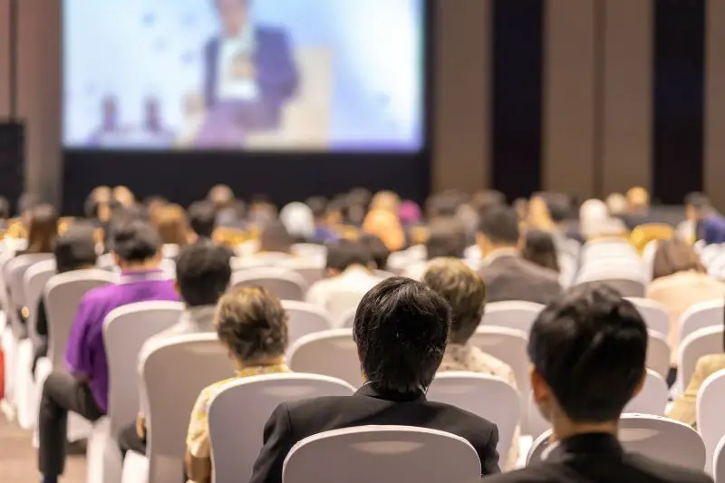 Rear view of Audience listening Speakers on the stage in the conference hall or seminar meeting