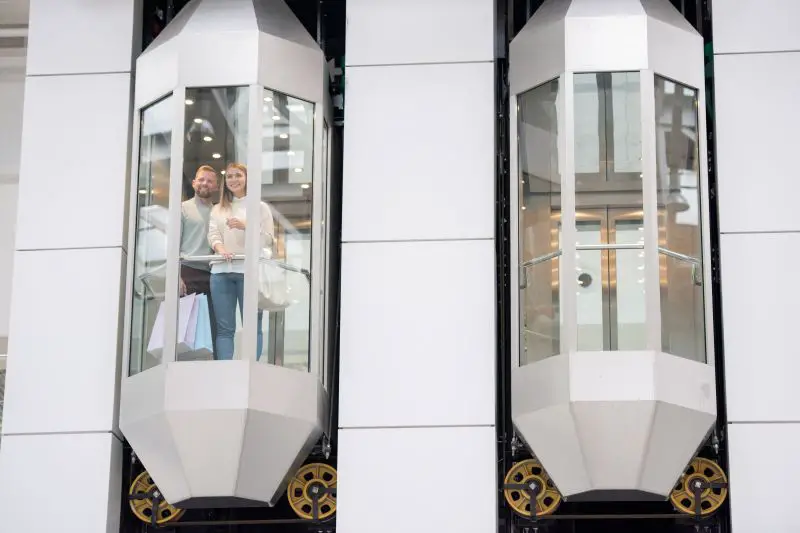 Young couple standing in one of elevators and looking through window