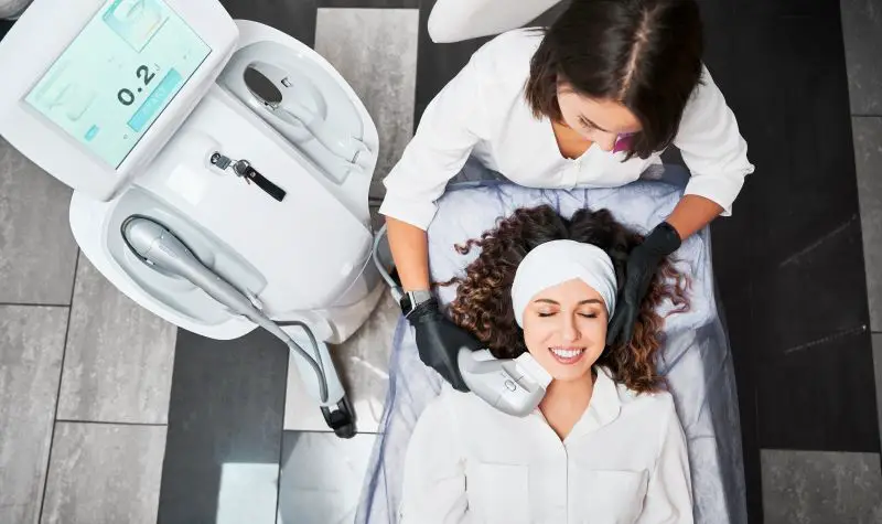 Attractive young woman receiving facial treatment in clinic.