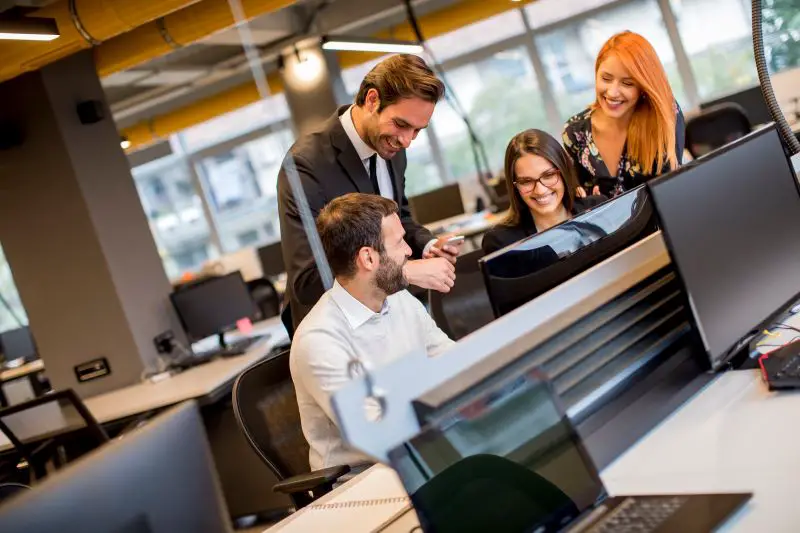 A group of cheerful office colleagues collaborating at a desk in a modern workspace