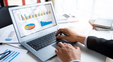Business professional analyzing marketing performance charts on a laptop using profit tracking software