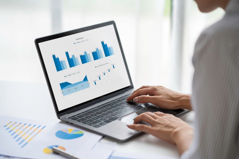 Investor reviewing adaptive investment strategy charts on a laptop, using real-time data analytics and performance metrics to inform portfolio decisions.