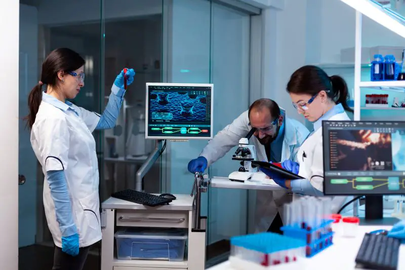Scientist analyzing blood sample in vacutainer with researching team