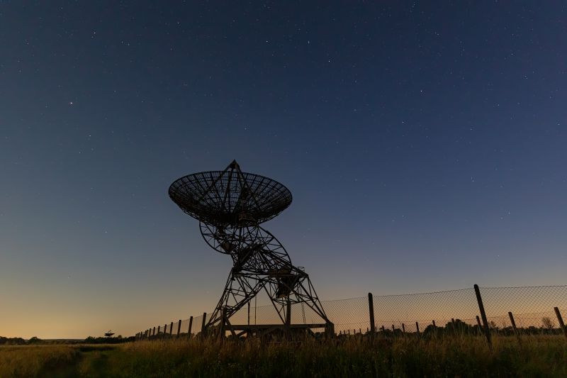 Silhouette of a large satellite dish at sunset