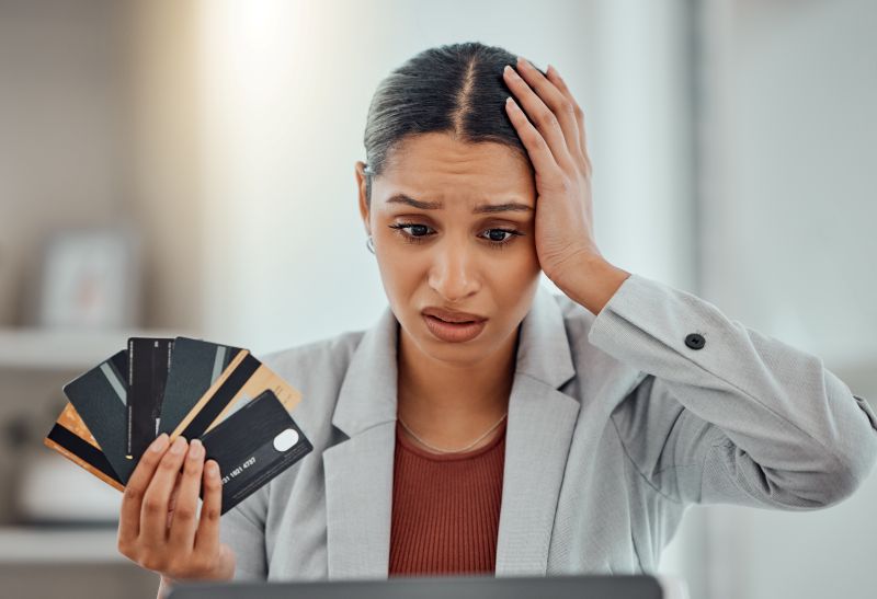 Worried businesswoman holding multiple credit cards while facing payment processor fund freeze issue