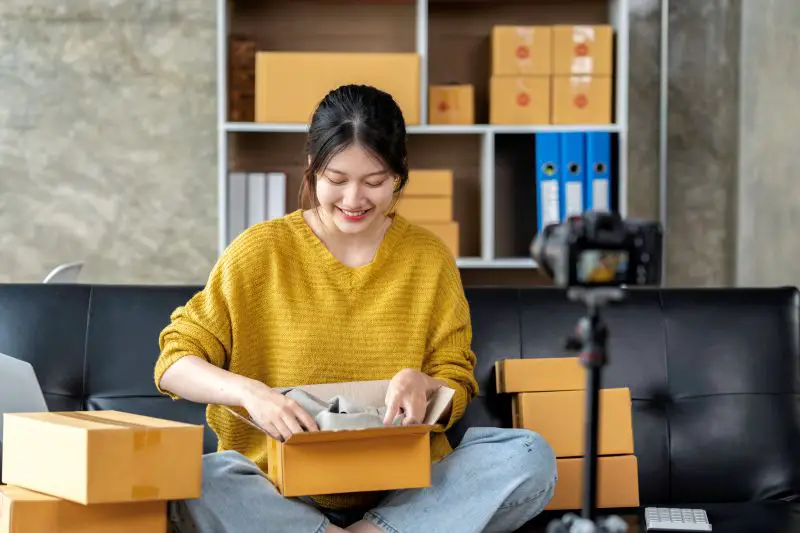 Startup SME small business entrepreneur of Asian young woman blogger showing clothes in front of the camera