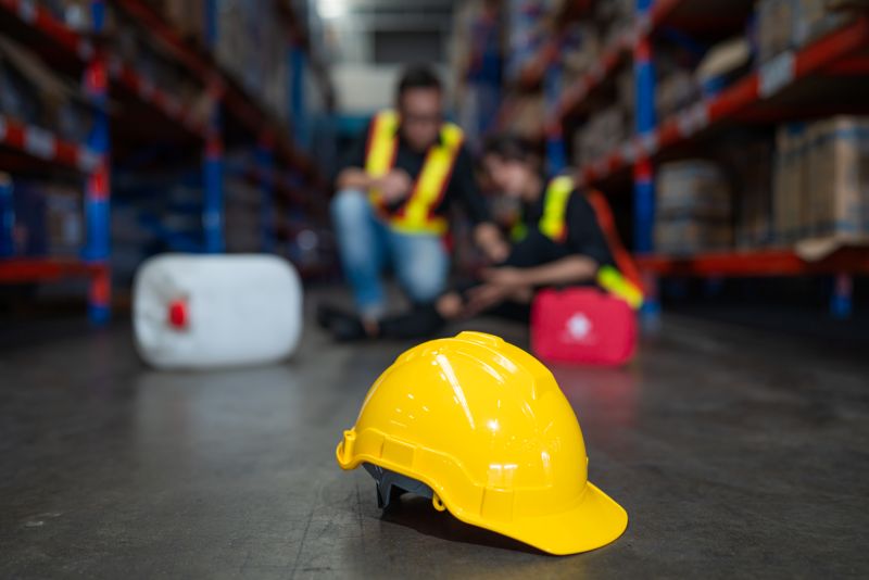 Mature foreman igiving first aid to staff suffering after working injury.