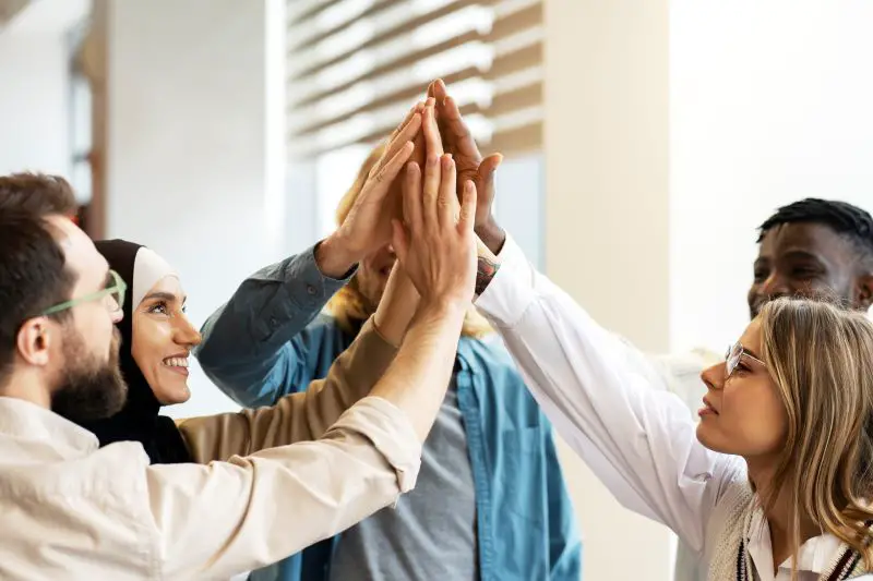 Diverse, multiracial group of people giving high five in modern office, Teamwork concept