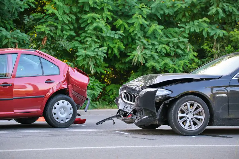 Damaged in heavy car accident vehicles after collision on city street crash site.