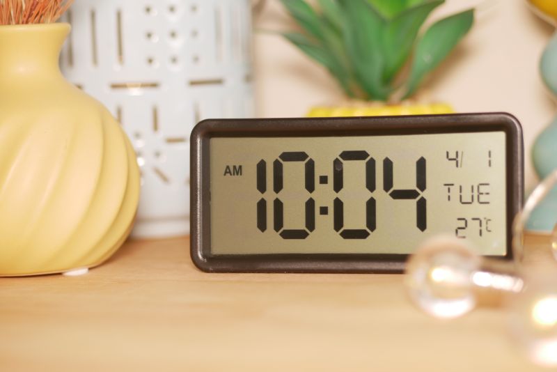 A digital clock shows 10:04 AM on a Tuesday in a warm room